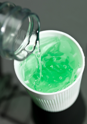 Filling white cup with aqua colored mouthwash